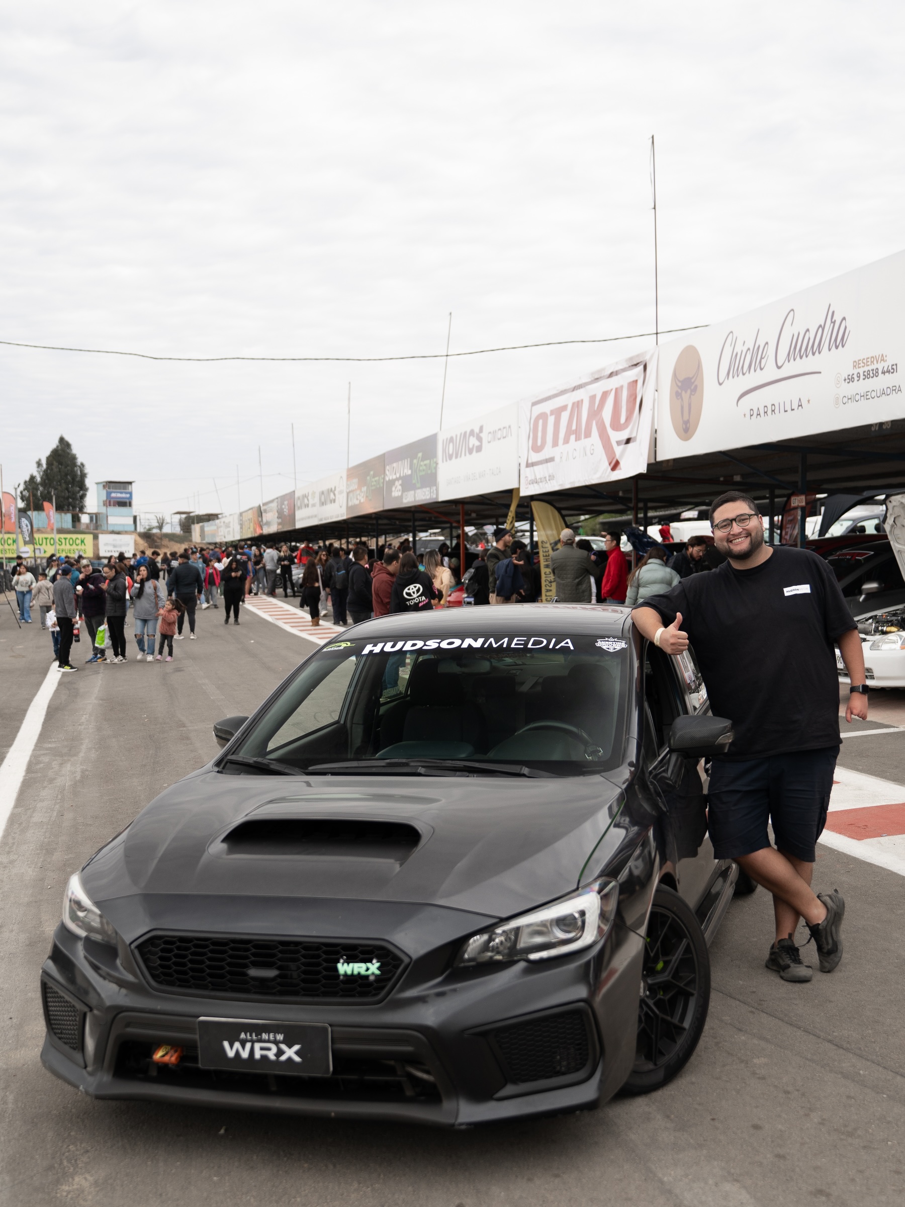 Gabriel Rojas junto a su Subaru WRX con el parabrisas rotulado Hudson Media, en el pit lane de un autódromo