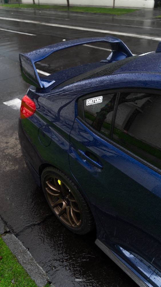 Subaru WRX STI en rolling shot bajo la lluvia, con reflejos en el pavimento, foto 02