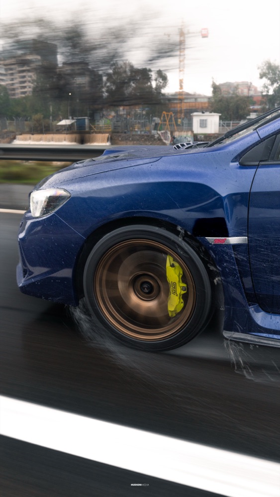 Subaru WRX STI en rolling shot bajo la lluvia, con reflejos en el pavimento, foto 06