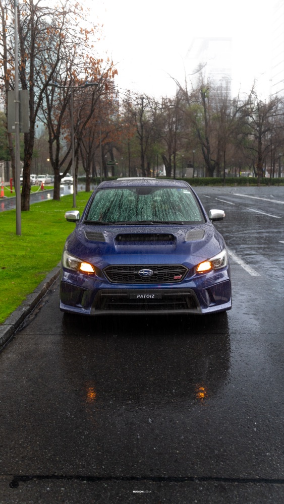 Subaru WRX STI en rolling shot bajo la lluvia, con reflejos en el pavimento, foto 07