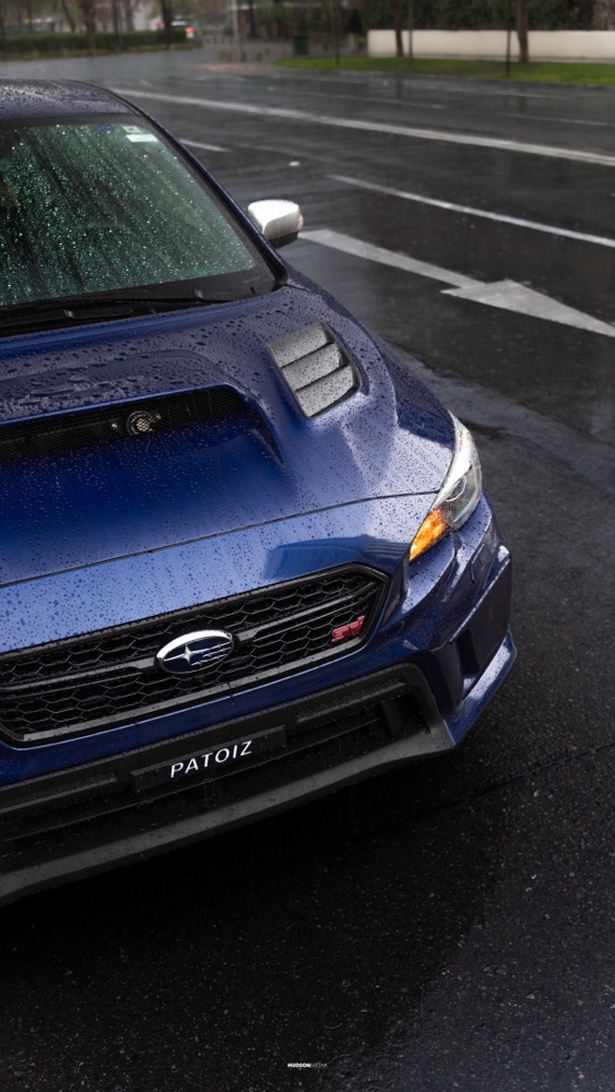 Subaru WRX STI en rolling shot bajo la lluvia, con reflejos en el pavimento, foto 08